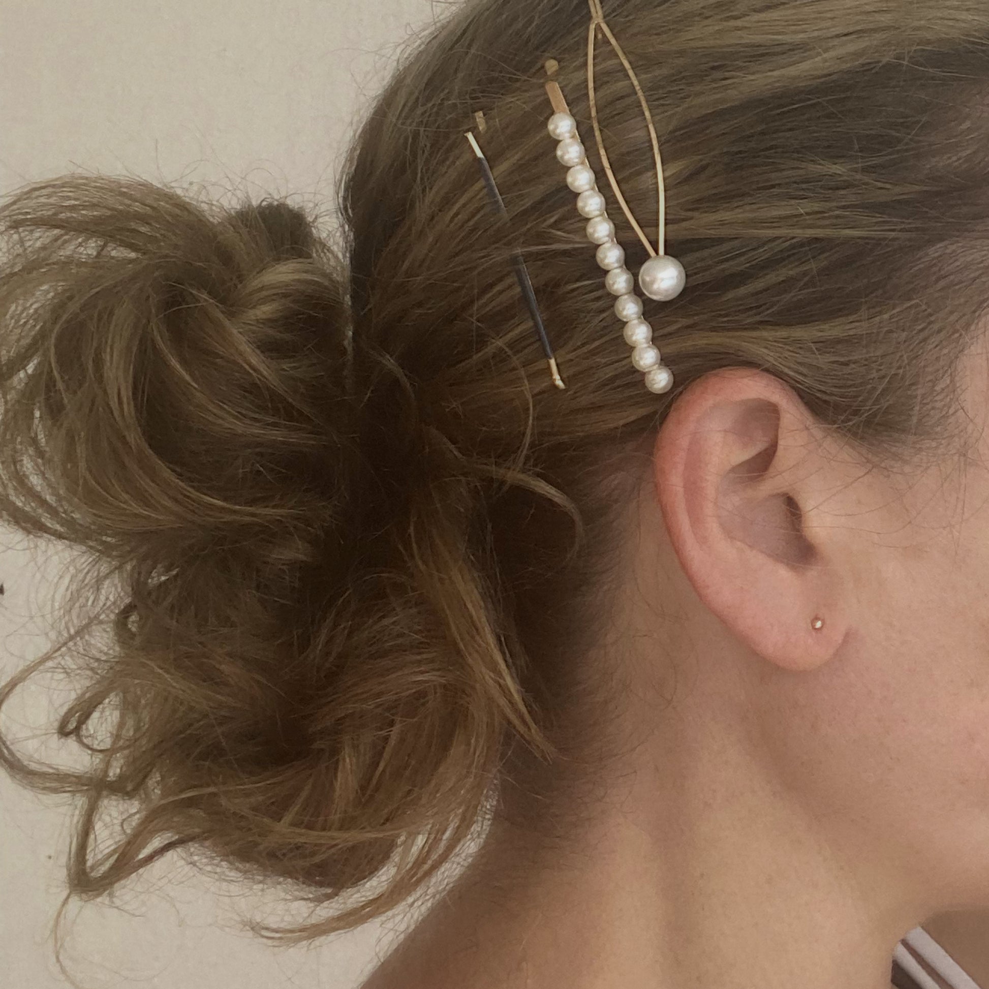 Close-up of a person's hair with decorative hairpins and earrings.