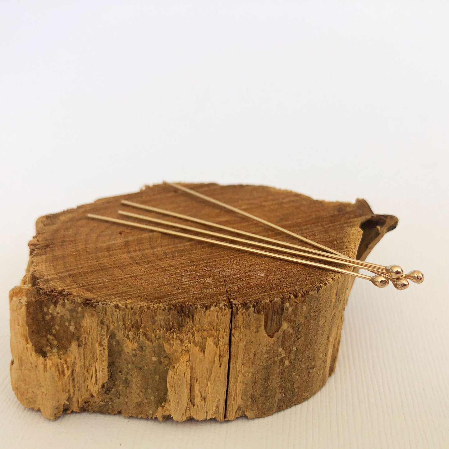side photo of 4 gold ball headpins displayed on a brown peice of wood.  Use this to  ake jewelry