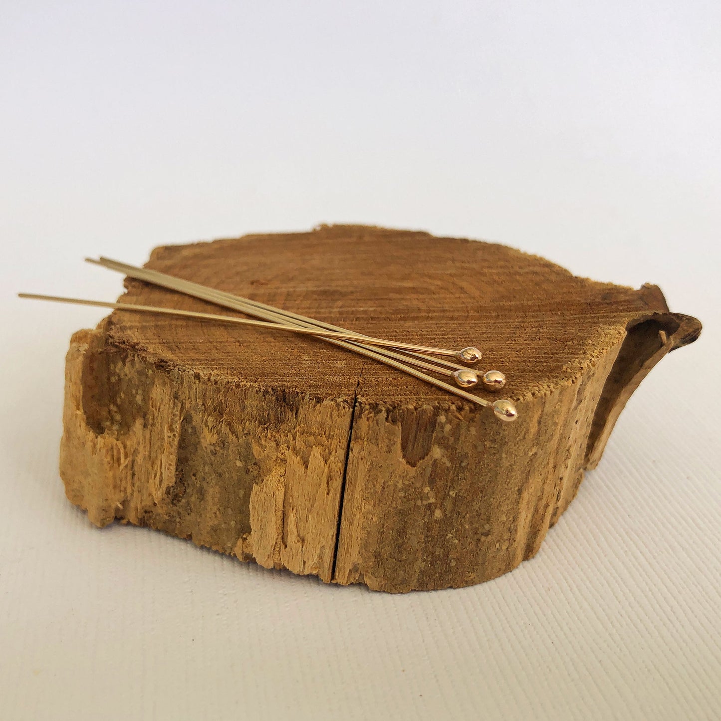 gold filled ball headpins resting on a wood block