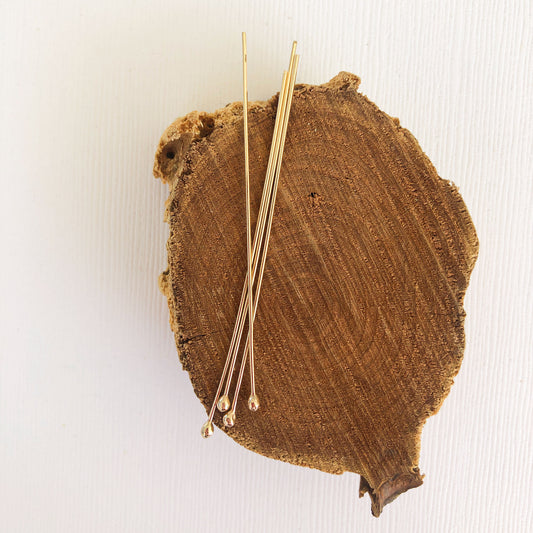 gold filled ball headpins resting on a wood block