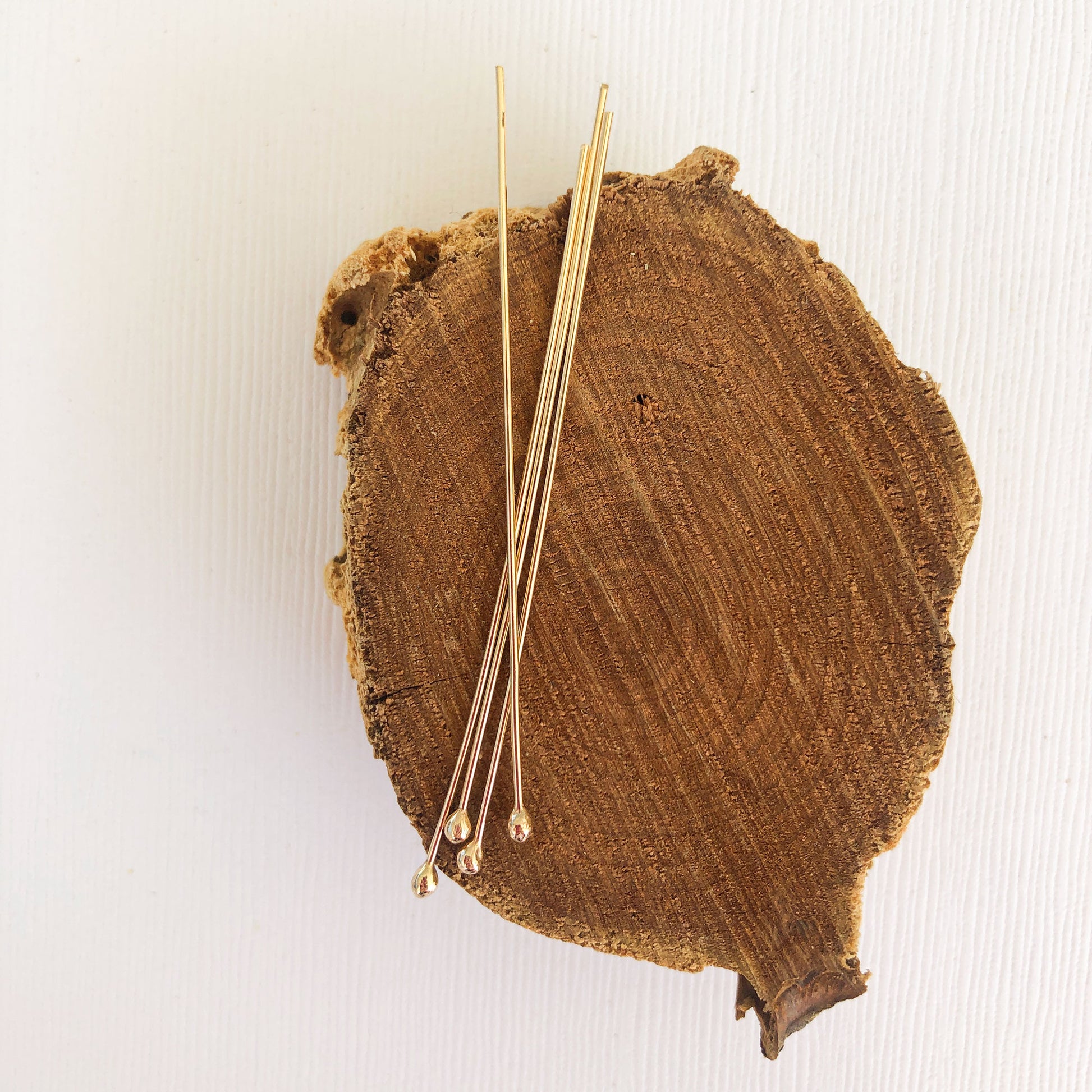 gold filled ball headpins resting on a wood block 