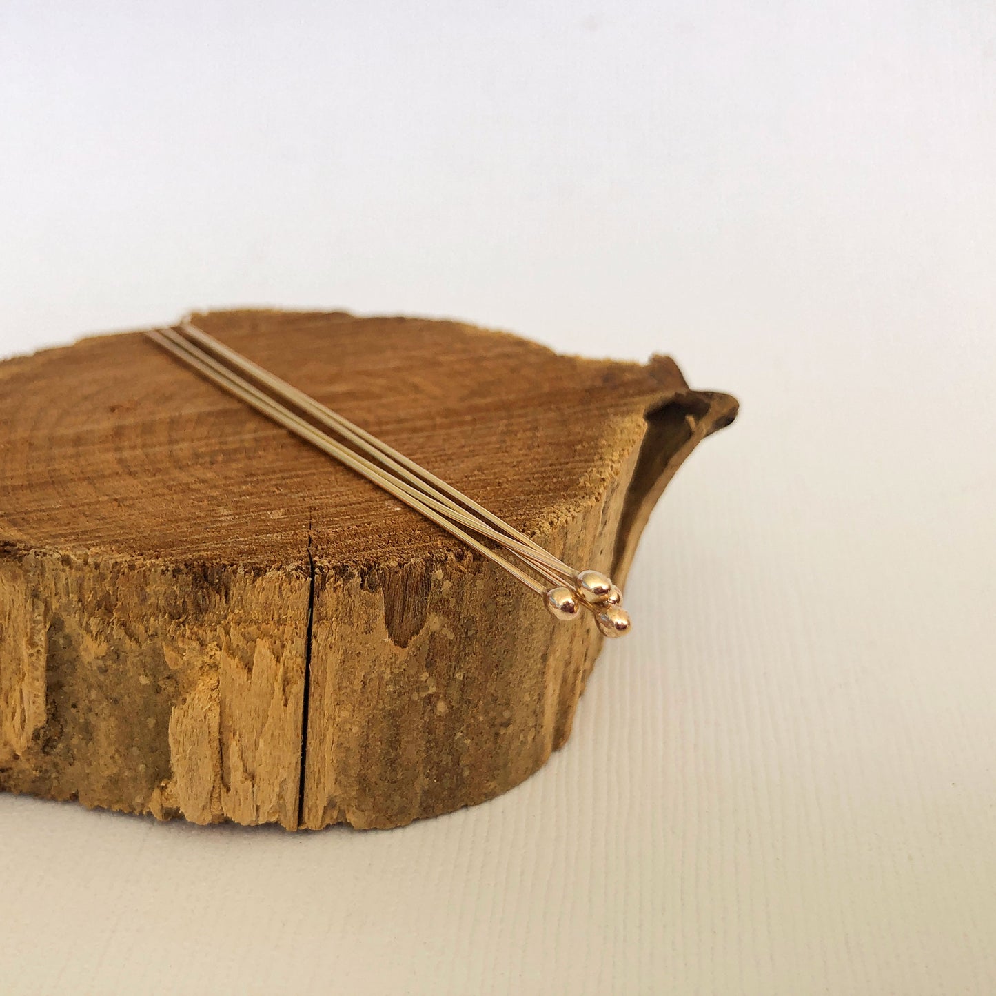 gold filled ball headpins resting on a wood block