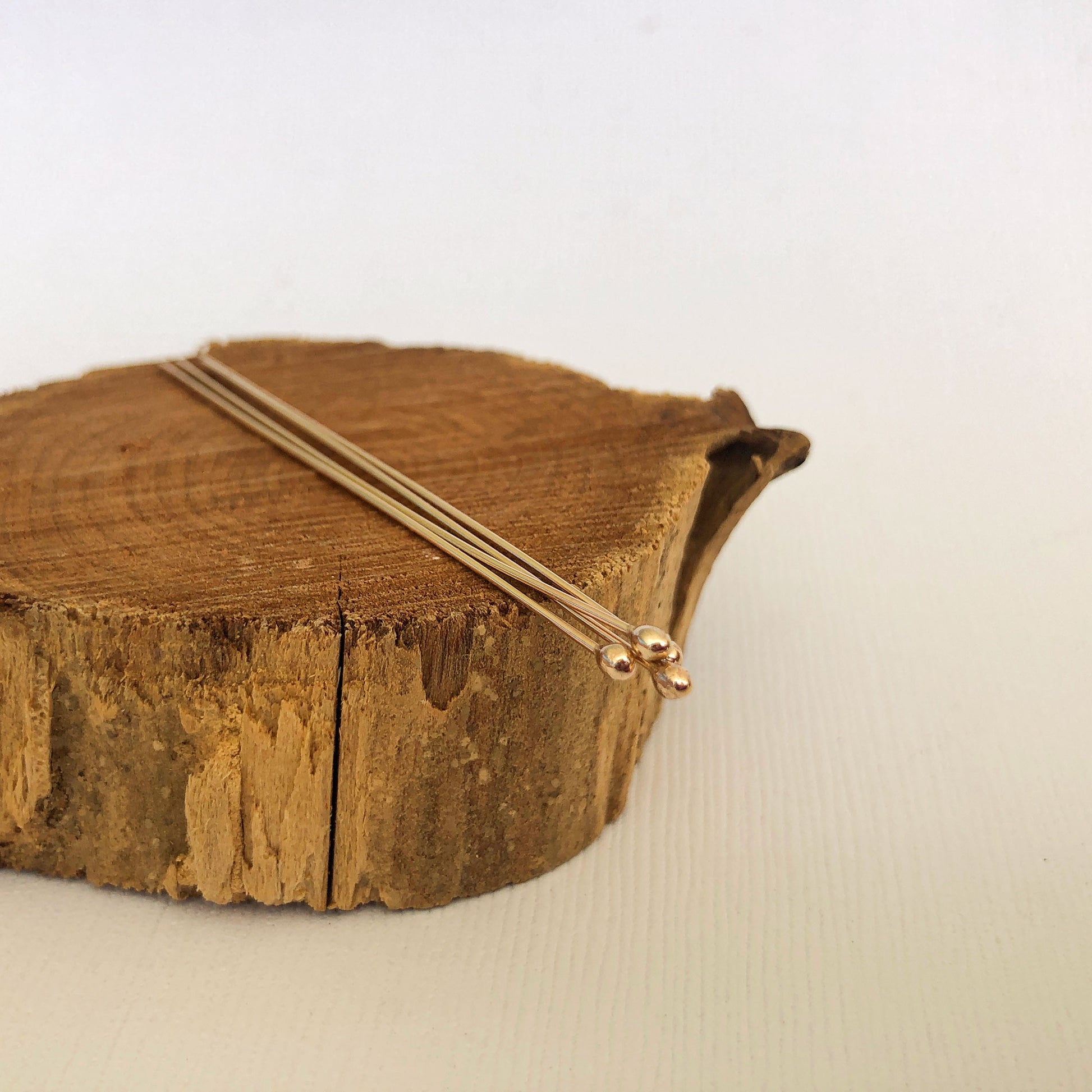 gold filled ball headpins resting on a wood block